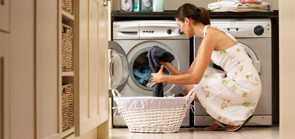 Woman loading washing machine in kitchen